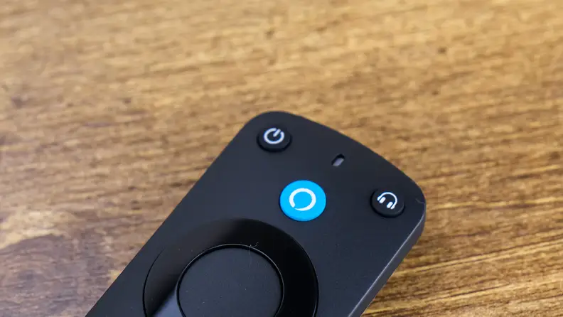 An Amazon Alexa Voice Remote Pro rests on a wood surface.