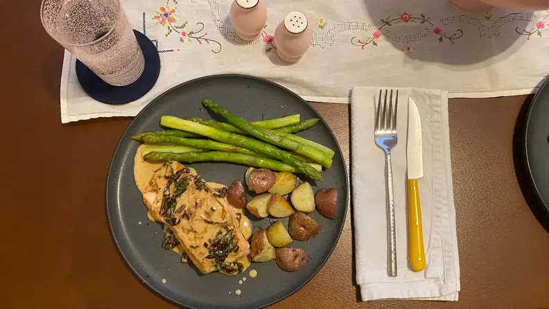 An overhead photo of salmon, roasted potatoes, and steamed asparagus on a dark grey plate.