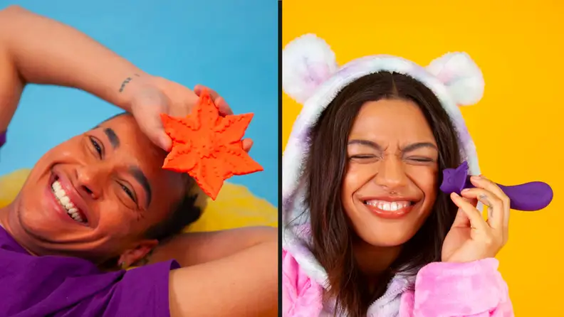 Two people holding bright colored objects next to their faces and smiling