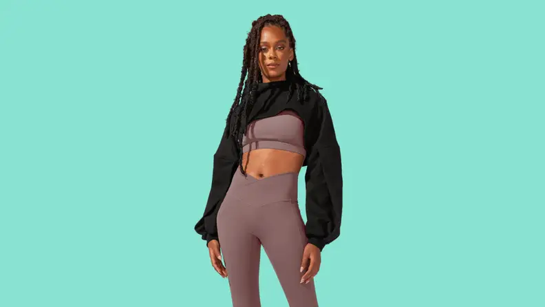 A model wearing a gray matching athletic set with a black cropped sweatshirt.