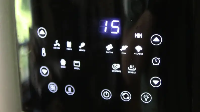 Control panel on the Kalorik 5-Quart Digital Air Fryer with assorted buttons lit up underneath the time display.