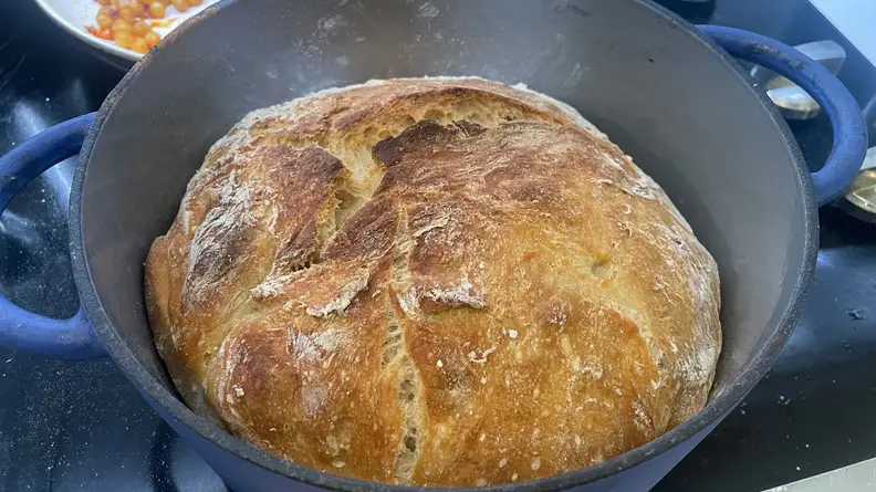 Fresh baked bread loaf inside of the Great Jones Dutch Baby oven.