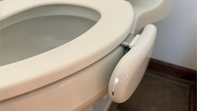 Side view of white toilet with Kohler Dekoda attached.