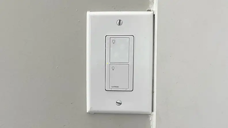 The Lutron Caséta Smart Light Switch hangs on a wall.