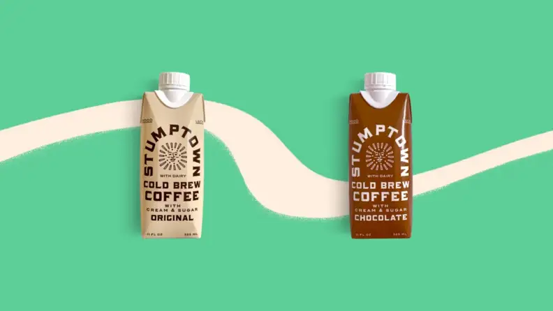 Two juice-box-style single-serve boxes of cold brew coffee on a green background.