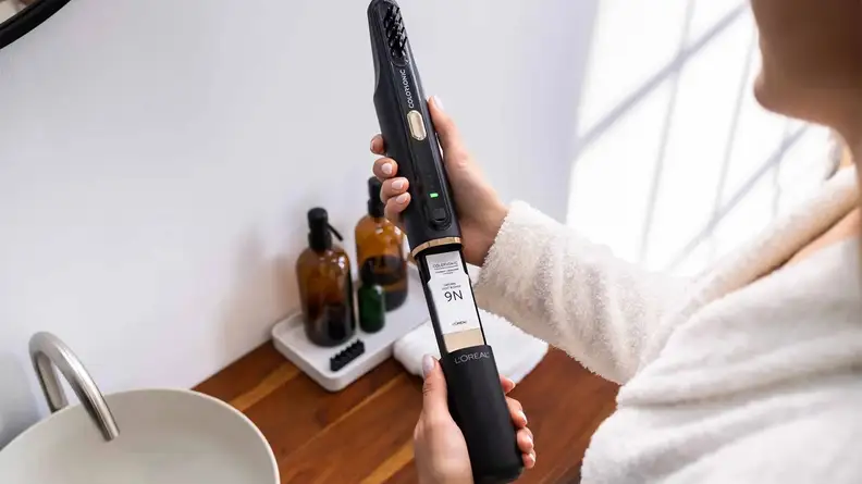 A person loading a cartridge labeled 9N into the L'Oréal Colorsonic hair device.