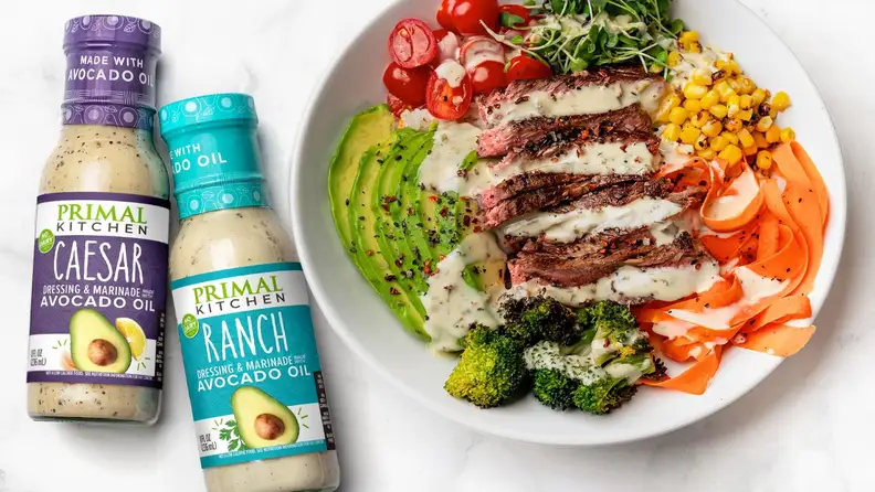Primal Kitchen Caesar and Ranch dressings beside a steak and vegetable bowl
