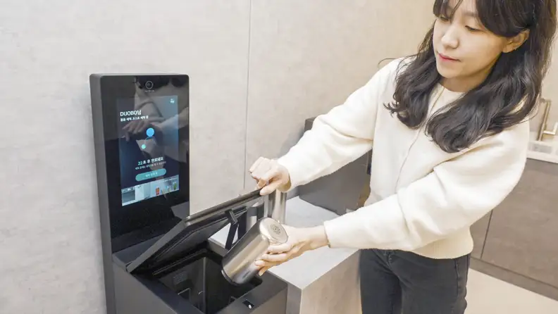 A person placing a tumbler in the LG mycup.