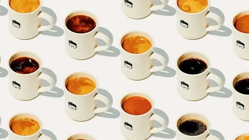Rows of mugs filled with different coffee drinks from above