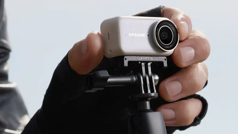 A gloved hand holds the Dreame Leaptic Cube action camera mounted on a Leaptic accessory grip.