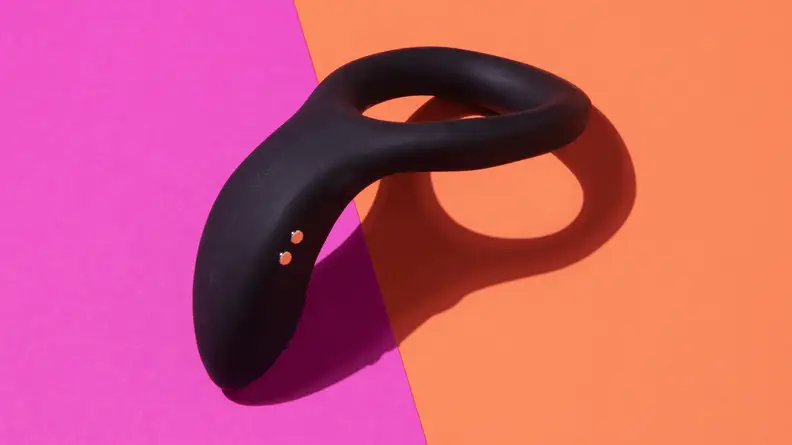 The Lovense Diamo vibrating cock ring on top of a pink and orange contrast surface.