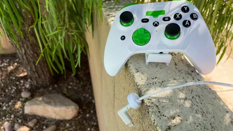 RiotPWR's Xbox Cloud Gaming Controller rests outdoors on a rock wall with its white cable arrayed in front of it.