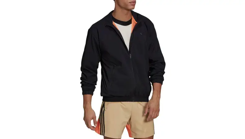 A model wearing a black adidas jacket with an orange pop of color at the collar.