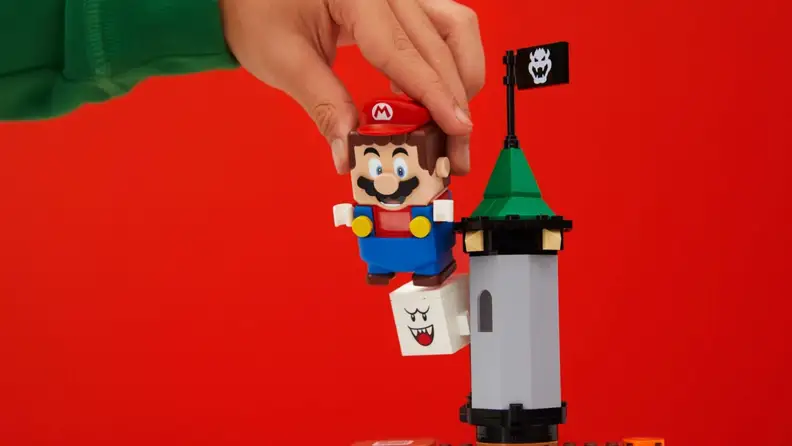 Lego Mario jumps on a Lego Boo character.