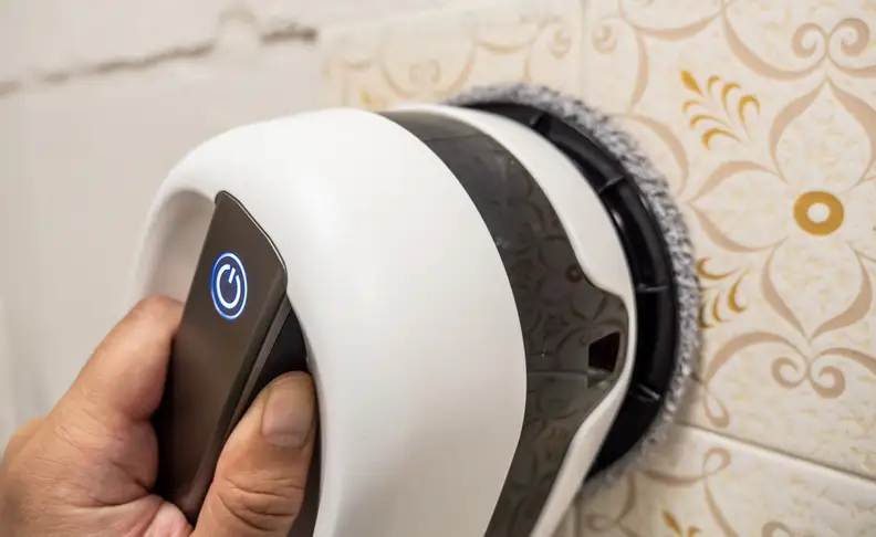 A user demonstrates how the handle on the back of the Jetbot Mop lets you lift it for buffing walls and other tricky surfaces.