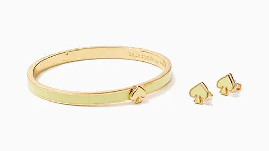 Golden bangle with a spade symbol on it next to two golden stud earrings with spade symbols