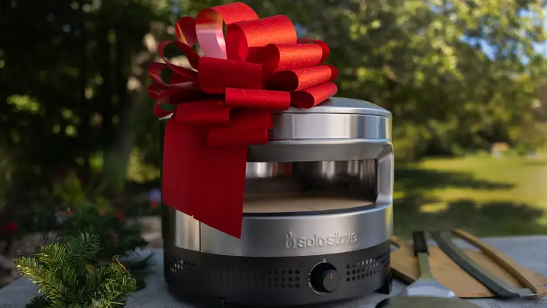 Close-up of a Solo Stove pizza oven decorated with a large red bow, making it a standout Christmas gift idea for anyone who loves backyard pizza nights.