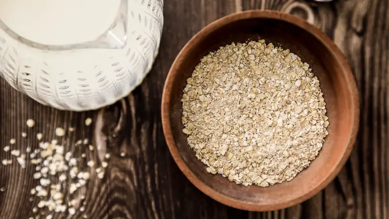 Bowl of oatmeal next to a glass pitcher of milk