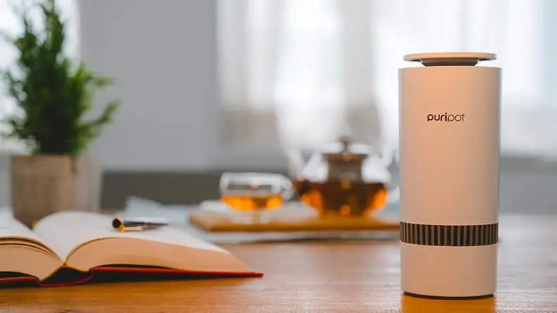 The Puripot M-Series air purifier sitting on a home desk.