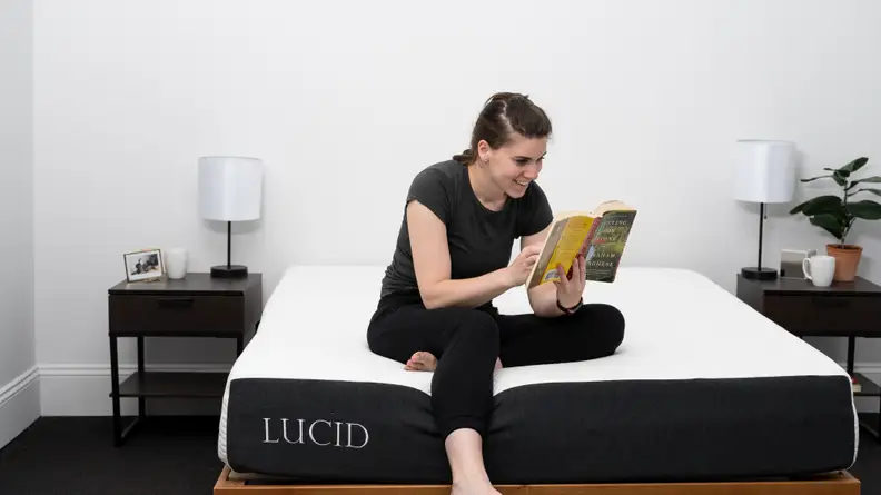 a person sits on the edge of the lucid mattress reading