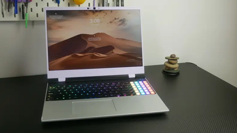 The Framework Laptop 16 on a black desk next to a stack of rocks.
