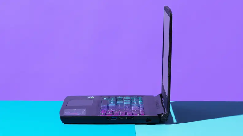 An open laptop viewed from a 90-degree angle against a blue and purple backdrop.