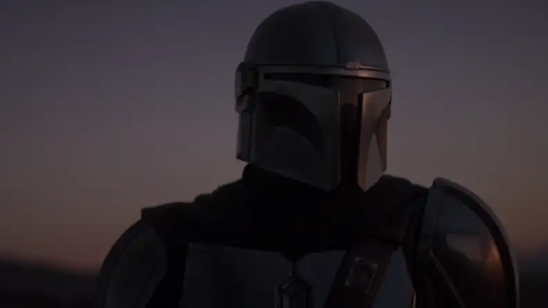 A screenshot from The Mandalorian series featuring the Mandalorian himself against a dark background.