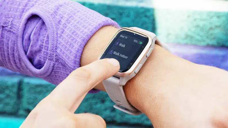 A person taps a Garmin Venu Sq 2 fitness tracker on their wrist.