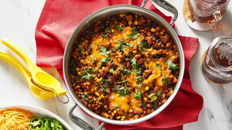 Silver pot with chili inside next to ingredients.