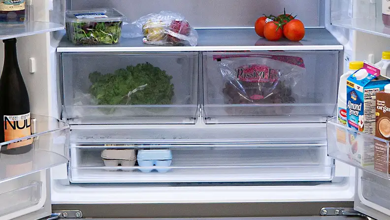 A close-up of the fridge's crisper drawers, stocked with fresh produce.