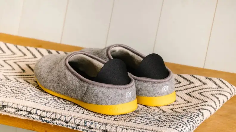 The backside of a pair of Mahabis Classic Men's Slippers, showing off yellow soles and logo.