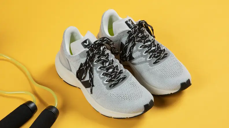 A pair of white running shoes sits next to a jumprope.