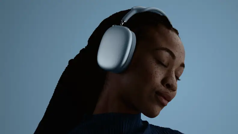 Woman listening to metallic blue over-ear AirPods Max 2 headphones.