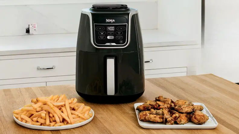 The Ninja Air Fryer XL with chicken wings and fries ready and served in separate plates.