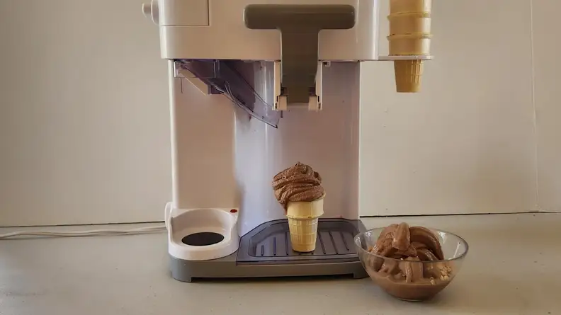 The Cuisinart Mix It In ICE-48 on a countertop surface with a chocolate soft-serve cone under dispenser.
