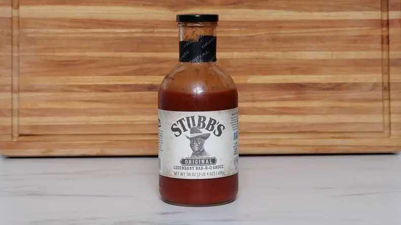 A bottle of Stubb’s Original Legendary Bar-B-Q sauce next to a wood cutting board.