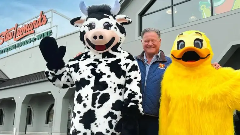 Cow and duck mascots posing with a man outside Stew Leonard's