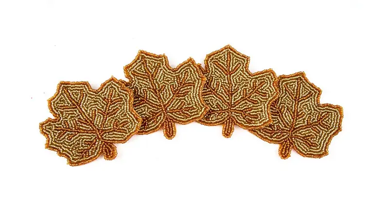 Four beaded coasters in the shape of autumn leaves.