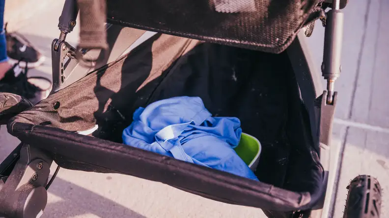A basket of a stroller filled with items for a child.