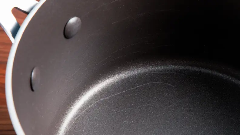 Dark nonstick interior of pot with multiple scratches.
