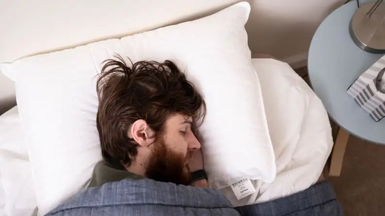 A man sleeping on Beckham hotel pillows.