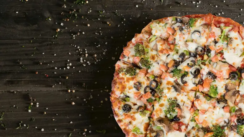 Close-up of a veggie pizza topped with broccoli, olives, and mushrooms
