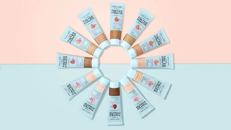 All of the shades of the Wet n Wild Bare Focus Tinted Hydrator are in a circle with a pink and blue background behind them.