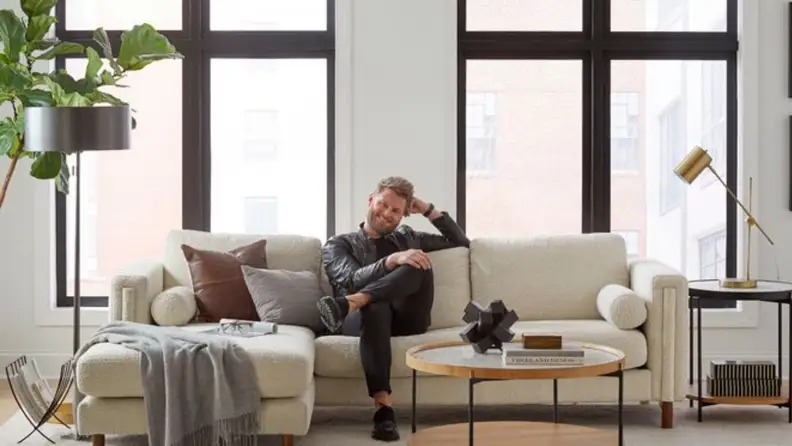 Bobby Berk sitting on a couch in a living room