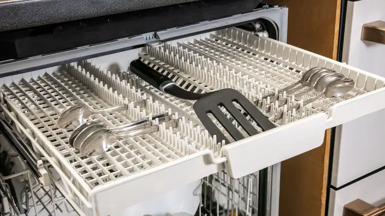 The photo shows the top rack of the dishwasher, with a number of spoons and a spatula.