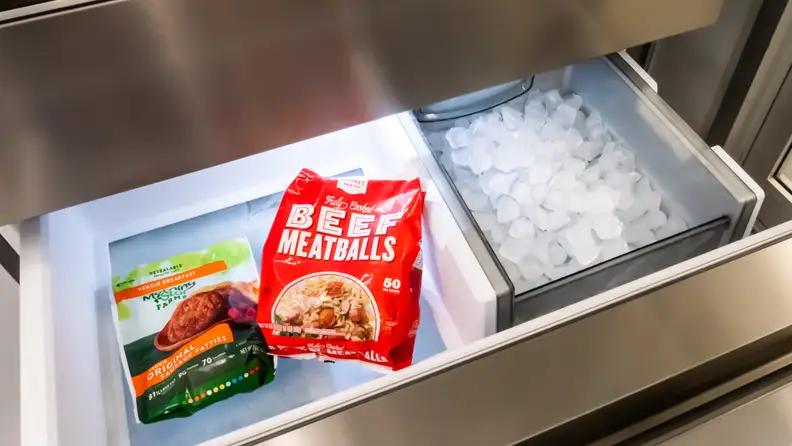 The Frigidaire Pro PRMC2285AF counter-depth French-door refrigerator's freezer drawer, with a few bags of frozen food on the left and a large ice reservoir off to the right.