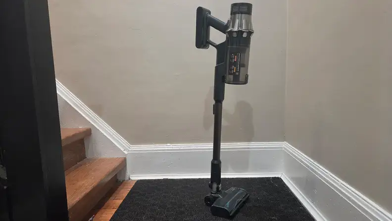 Yaber HP20 cordless vacuum standing upright next to wooden stairs.