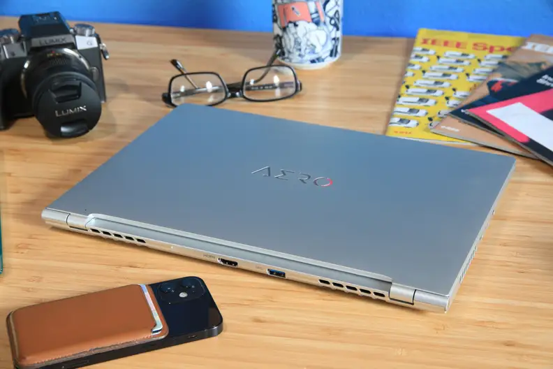 The Gigabyte Aero 14 OLED laptop closed, surrounded by office supplies on a desk.
