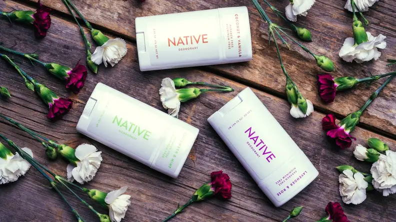 Native Deodorant laying next to flowers on wood