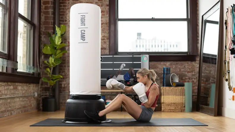 Woman exercising with Fight Camp punching bag at home.